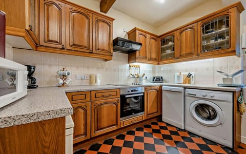 Kitchen with washing machine, dishwasher, kettle, toaster, oven and microwave. Pine wall and base units