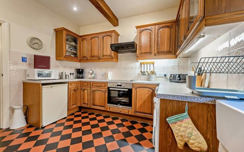 Fitted kitchen with tiled floor: fridge, microwave, oven, coffee machine, kettle and toaster