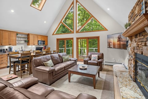 Cozy mountain-style open floor plan great room with fireplace and stunning forest views