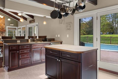 Open Kitchen with Butcher Block Island (main house). Doors to Pool Deck and Grill