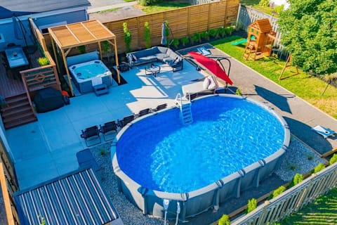 This private backyard oasis features an expansive patio with a built-in hot tub and a comfortable outdoor lounge area. Includes a children`s play set, a BBQ grill, and a well-maintained lawn. Perfect for family fun and relaxation.