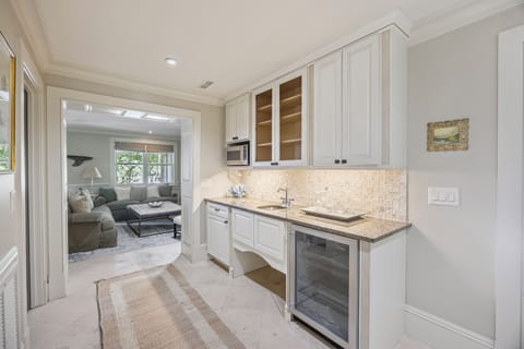 Wet bar area with microwave, sink, and wine cooler.