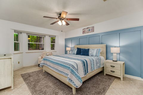 Welcome to a tranquil retreat where the comfort of a plush king-sized bed with chic blue and white bedding invites you to relax, and serene views of nature await just outside the windows.