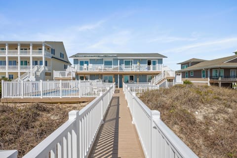 Elevated boardwalk leads through coastal dunes to beachfront vacation homes, offering convenient beach access in this waterfront community.