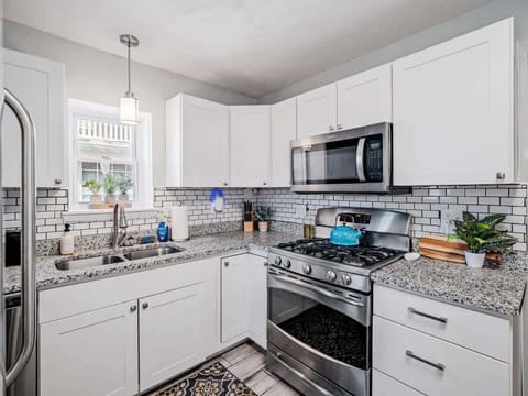 Bright, modern kitchen with crisp white cabinets, granite countertops, and subway tile backsplash. Stainless appliances and patterned wood-look floors flow seamlessly into the adjacent dining room for effortless entertaining! ️✨