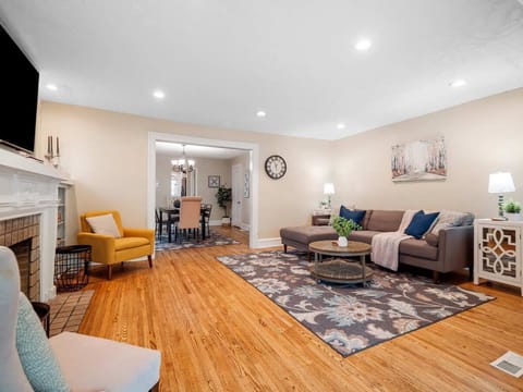 Bright and cozy living room with a comfy sectional ️, floral rug , and a charming fireplace . Open layout flows into a stylish dining area — perfect for relaxing or entertaining ✨.