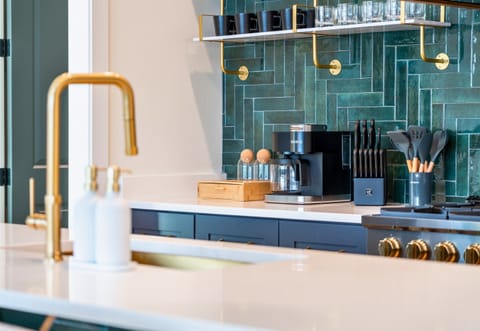 A Modern Style Kitchen With Gold Fixtures And A Stylish Backsplash.
