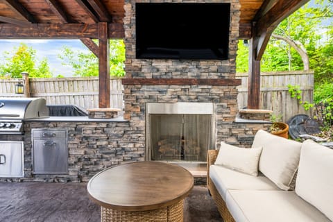 Gather under the stylish pavilion featuring a stone fireplace, TV, and grill for the ultimate outdoor hangout 🍔🔥📺