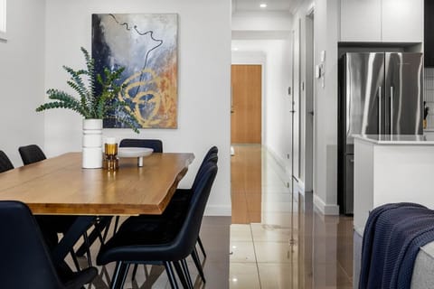 The scene extends to a sleek kitchen area with stainless steel appliances and a hallway leading to other rooms, creating a stylish and contemporary home environment.
