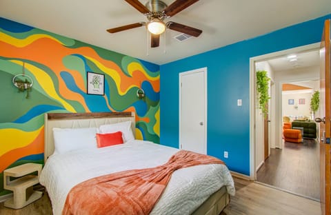 Eclectic bedroom with vibrant mural and plush beddings and ceiling fan