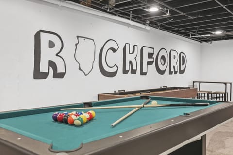 Basement rec room with shuffleboard, PacMan, pool table, smart TV, and sofa seating.