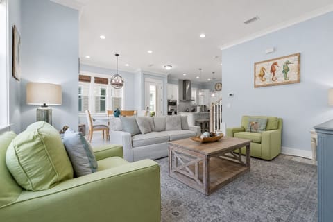 A spacious and beautifully decorated living area with soft pastel tones, modern furniture, and an open-concept design.