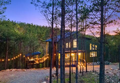 Glowing string lights and the soft warmth of the cabin’s interior make the home shine against the nighttime forest backdrop.