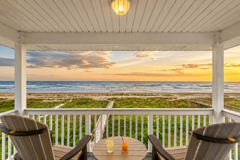 Covered beachfront balcony with sunset Gulf views, outdoor seating, and direct sightlines over the dunes for a relaxing Galveston vacation rental experience.