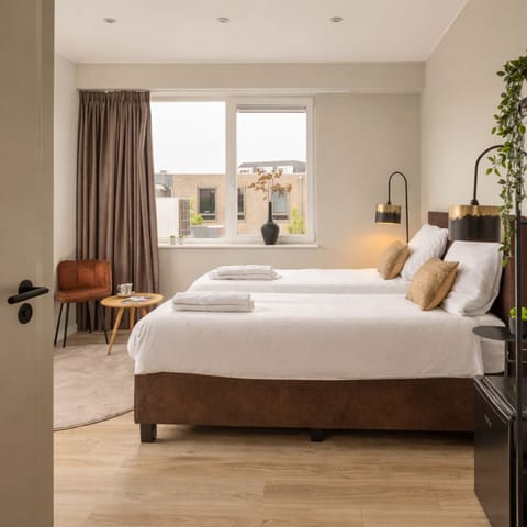 Cozy bedroom with box-spring bed, warm lighting and soft linens — perfect stay in Raamsdonksveer near shops and restaurants.