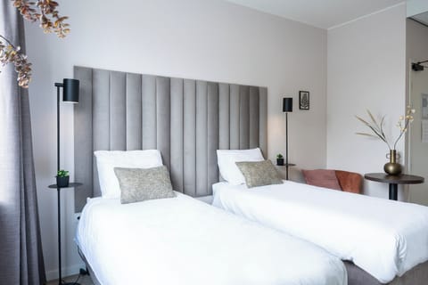Comfortable twin beds with elegant headboards, complemented by soft lighting and a stylish seating area for relaxation.