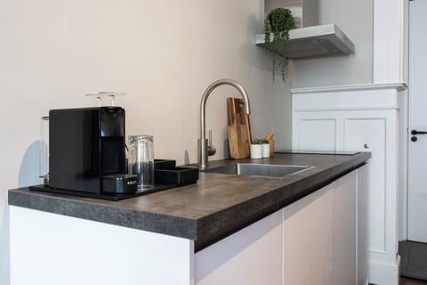 Fully equipped kitchen with contemporary appliances, including a coffee machine and sleek countertops, ideal for preparing meals or enjoying a coffee.