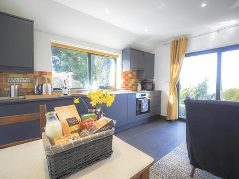 Kitchen area on one side with table and chairs, welcome pack and sofa on the other side