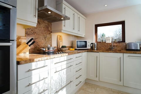 Kitchen at Glandwr with oven, microwave, kettle and kitchen equipment, tiled floor
