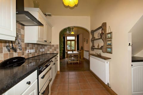 Fitted kitchen with cooker; leading to dining area with table and seven chairs