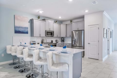 Bright modern kitchen with stainless appliances, island seating, and stylish decor
