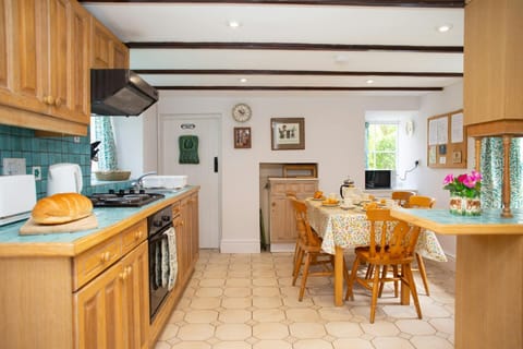 Fitted kitchen with electric oven and extractor hood, kettle and toaster, dining table with five chairs