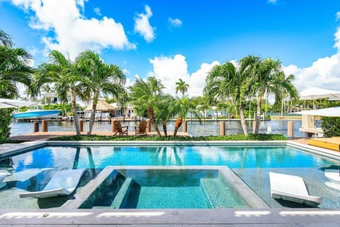 Luxury resort-style pool with a spacious Baja deck, lush palms, and chic lounge seating.