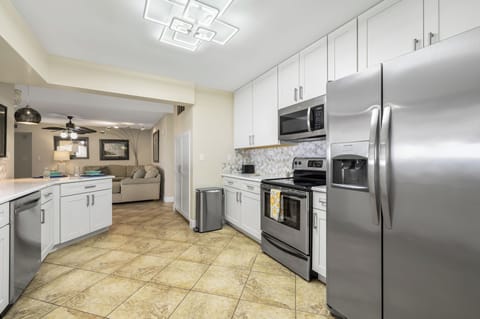 - Sleek stainless steel appliances including fridge, oven, and microwave
- Plenty of cabinetry and tiled flooring make cooking and cleanup seamless
- Convenient access to the living area and dining spaces from every angle