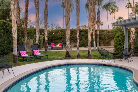 Twilight pool with palm-framed lawn, lounge chairs, and glowing fire pit — the shot you'll screenshot before you book