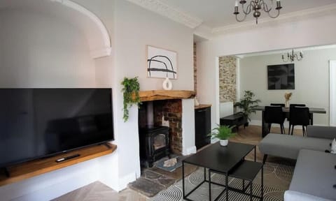 Elegant living and dining space with a cozy fireplace, modern furnishings, and a large TV. Stylish, spacious, and inviting.