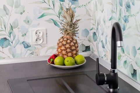 Decorative kitchen detail with floral wallpaper, black sink and a bowl of fruit.