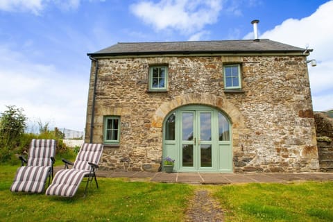 Stone built coach house with doors leading to lawn area with garden loungers