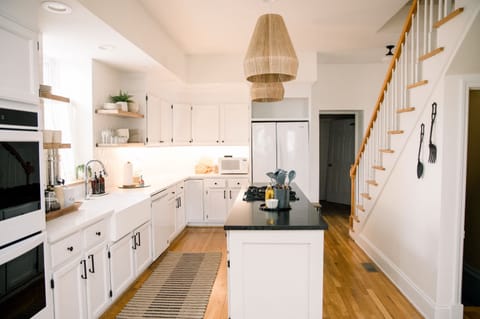 Spacious kitchen with crisp white cabinets, open shelving, and center island—the perfect hub for group cooking and conversation 🍽️