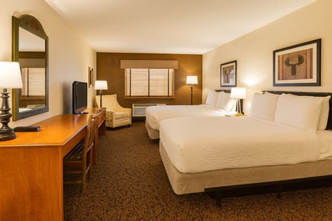 Unwind in a bright double-queen room with warm lighting.