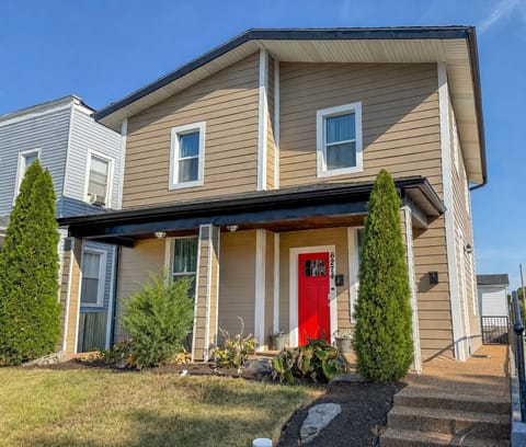 Charming two-story home with a bold red door and welcoming front porch