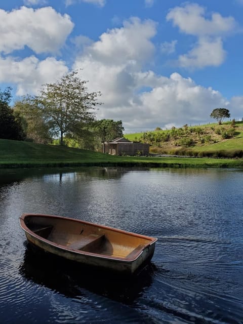 Across the pond, the cabin glows peacefully, reflected in the calm water.