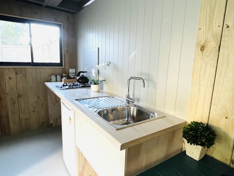 Kitchenette with mini fridge, toaster, and gas kettle. Enter to outdoor dining.