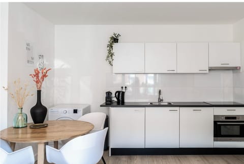 Fully equipped kitchenette at Hastelweg Eindhoven with cooking essentials, a clean worktop, and a cozy dining table for meals or laptop work.