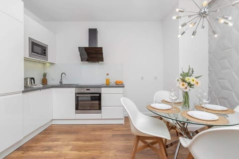 A compact, white kitchen and dining space with a modern round table and chairs.