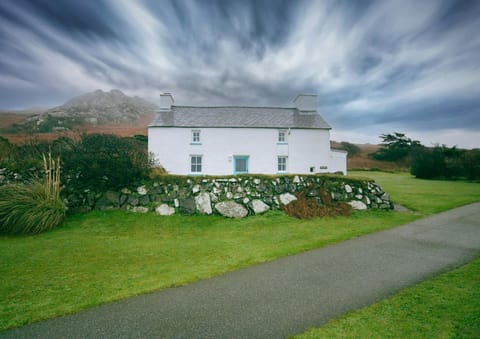 Tal Y Gaer Cottage with white walls and blue front door surrounded by countryside