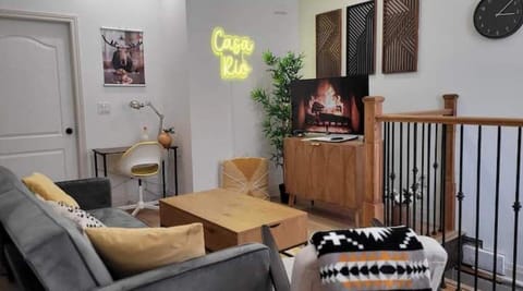 The main living area, with sofabed, coffee table, SmartTV, office desk and neon.