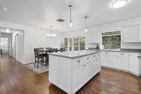 Cook with a view in this stunning white kitchen featuring a massive granite island, custom cabinetry, and a bright dining space, it’s the perfect hub for modern living and entertaining.