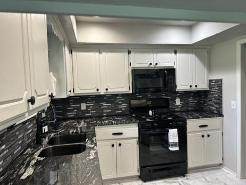 Kitchen with gas stove stocked with dishes, pots, pans, seasonings, etc.