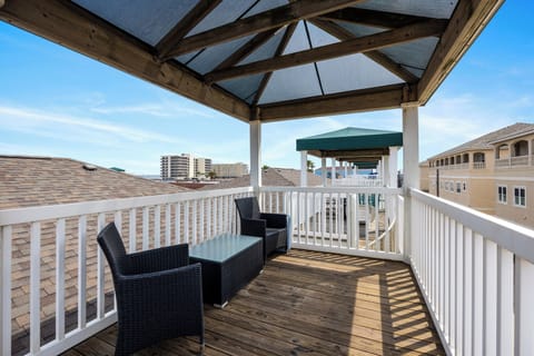 Step onto your private covered balcony where morning coffee feels magical with wicker seating and coastal views stretching beyond rooftops.