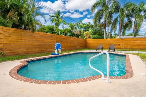 Serene pool view with lush surroundings, elegant outdoor seating .