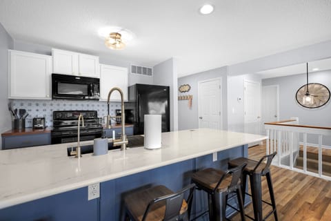 Modern kitchen with eat in bar and oven, dishwasher, microwave and refrigerator.