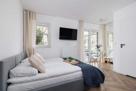 A bright bedroom area with a double bed, sofa, and large windows letting in plenty of natural light.