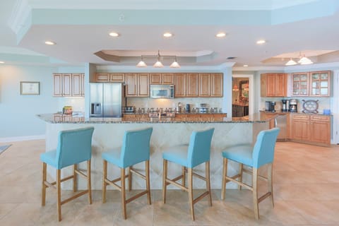The modern kitchen features a large island with light blue bar stools and modern appliances, creating an inviting atmosphere