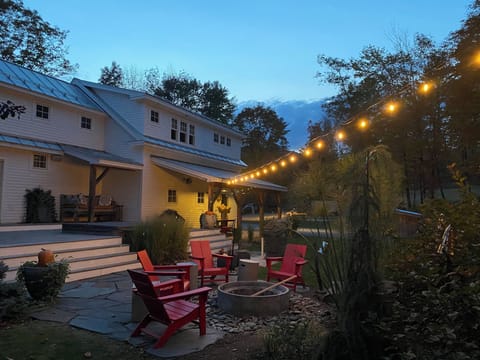 String lights light the hot tub in the backyard. There is a gas grill. 