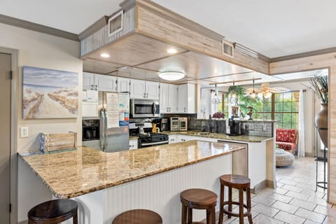 Fully stocked kitchen with 4 stools at the counter.